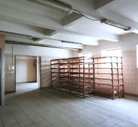 Production premises with shelves and an elevator, illuminated by windows, with ceramic flooring.