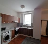 Kitchen of a 2-room apartment with a kitchen unit, washing machine, refrigerator, and floor with wooden decor.