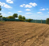 Residential plots in Pravotice with cultivated land, green hedges, and blue skies.