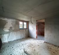 The interior of a family house under construction with unfinished plaster and concrete floor.