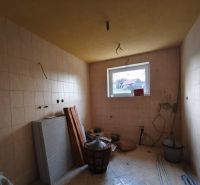 Room in a family house with tiles, a window, building materials, and furnishings.
