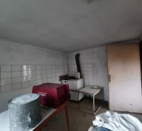 A room in a family house with a table, a bucket, and tiles on the wall.