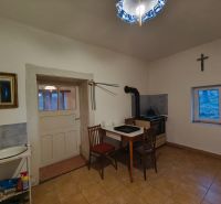 A kitchen in a family house with a stove, a simple table, and a chair.
