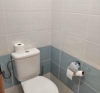 A bathroom with light tiles and a toilet in a 2-room apartment.