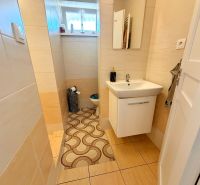 A bathroom with beige tiles and a wooden decor floor in a family house.