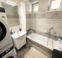 Bathroom in a family house with a bathtub, sink, and a washing machine with a dryer.