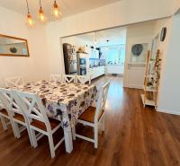 Dining room with wood-patterned flooring in a family house, with chairs and a dining table.