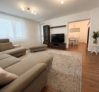 Bright living room with a corner sofa and a wooden decor floor in a family house.