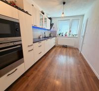 A kitchen in a family house with white cabinets and a floor with a wooden decor.