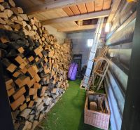 Wooden interior of a cabin with a supply of wood and tools.