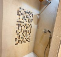 A shower corner with mosaic on the wall in a cottage.