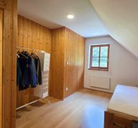 A room with wooden paneling and a floor with a wood decor, a bed and a window.