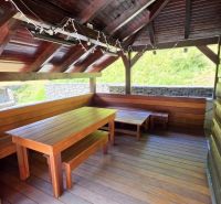 The exterior of the cottage in Jarabej with a wooden shelter and seating area.