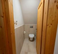Interior of a cabin with a toilet, light tiles, and wooden paneling on the door walls.