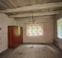Old wallpaper, wooden ceiling, shelf, and wardrobe in a room of a family house.