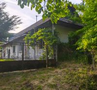 A family house in Čelovce surrounded by greenery and a metal fence.