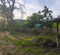 A peaceful garden plot by a family house in Čelovce with trees and a shelter.