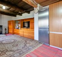 Interior of a family house with a fireplace and wooden ceiling, complemented by a carpet and a bookshelf.