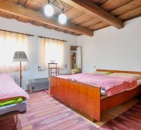 A bedroom in a family house with a wooden ceiling and comfortable beds.