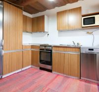 A kitchen in a family house with wooden cabinets and a refrigerator.