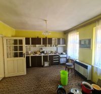 A kitchen in a family house with yellow walls, a brown carpet, and a kitchen unit in Dolné Otrokovce.