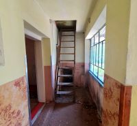 A narrow hallway with a ladder to the attic in a family house.