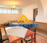 Interior of a family house with a tiled stove, table, chairs, and a floor with a wooden decor.