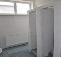 A bathroom in a production area with a tiled floor and several sinks.