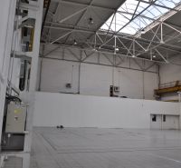 Interior of manufacturing spaces with high ceilings, flooring, and natural light from the roof.