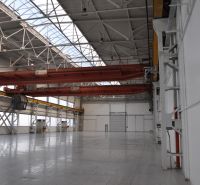 An industrial hall in production premises with two cranes and a glass roof.
