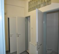 Open door to the restroom in the production area with tiles and a sink.