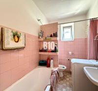 A bathroom in a family house with pink tiles and a bathtub.