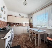 A kitchen in a family house with seating, tiles, and decorative plates on the wall.