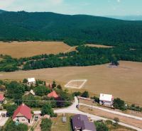 A rural view of residential plots in Podhradie surrounded by forests and meadows.