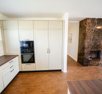 A kitchen in a family house with a fireplace wall and a wooden decor floor.