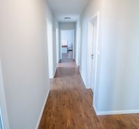 A hallway in a family house with a wooden decor floor and white walls.