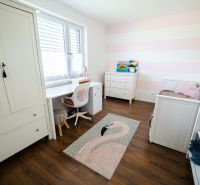 Children's room with white furniture and a wooden decor floor in a family house.