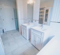 A bathroom with two sinks, a bathtub, and tiles in a family house.