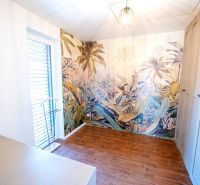 A room in a family house with exotic wallpaper and a wooden decor floor.
