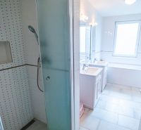 A bathroom in a family house with a bathtub, shower, and sinks.