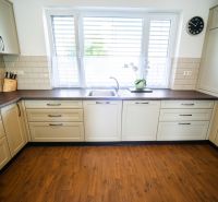 A kitchen in a family house with beige cabinets and a wood-patterned floor.