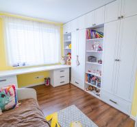 Children's room with a bed, shelving cabinet, and floor with wooden decor in a family house.