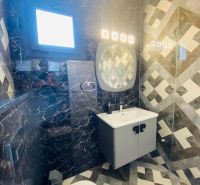 A bathroom in a family house with a sink, patterned tiles, and a window.