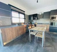 A kitchen with wooden decor, modern appliances, a spacious table, and gray cabinets.