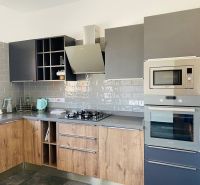 A kitchen with a wooden decor floor and gray cabinets in a family house.