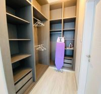 A wardrobe in a family house with shelves, hangers, and an ironing board.