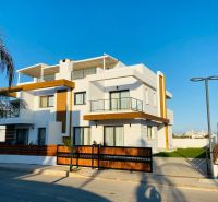 A family house in Yeni Boğaziçi with a white facade, wooden elements, and palm trees on the property.