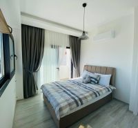 A bedroom with a large window, curtains, and a wooden decor floor in a family house.