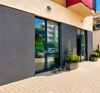 Commercial premises on Okružná Street in Stupava with a modern facade and flowers in front of the entrance.