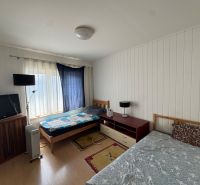 A bedroom in a family house with beds, a television, and a floor with a wooden decor.